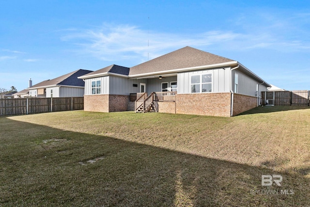 rear view of house with a yard, a ceiling fan, brick siding, and a fenced backyard