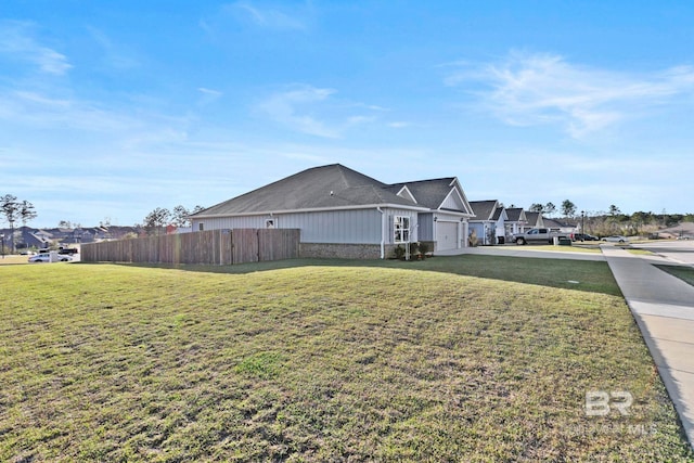 view of side of property featuring an attached garage, fence, and a lawn