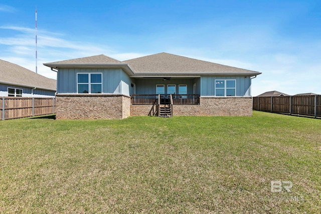 rear view of property featuring a lawn, brick siding, and a fenced backyard