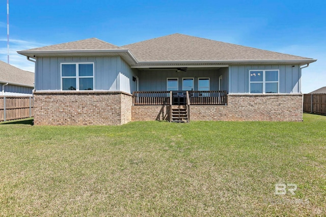 back of house featuring brick siding, a lawn, a ceiling fan, and fence