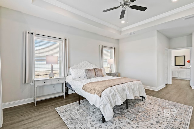 bedroom featuring wood finished floors, baseboards, a tray ceiling, recessed lighting, and ornamental molding