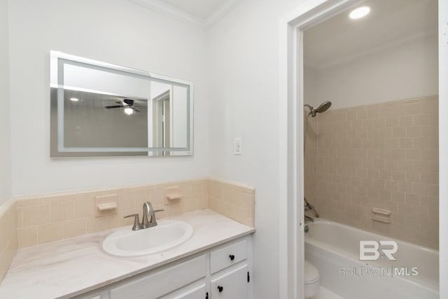 full bathroom featuring tiled shower / bath, vanity, ornamental molding, and toilet