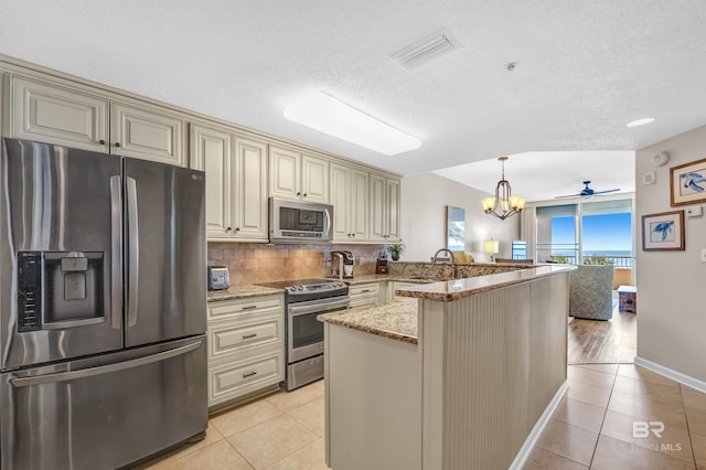 527 Beach Club Trl Unit C305, Gulf Shores, AL 36542 - kitchen featuring stainless steel appliances, backsplash, cream cabinetry, light stone countertops, and light tile patterned floors