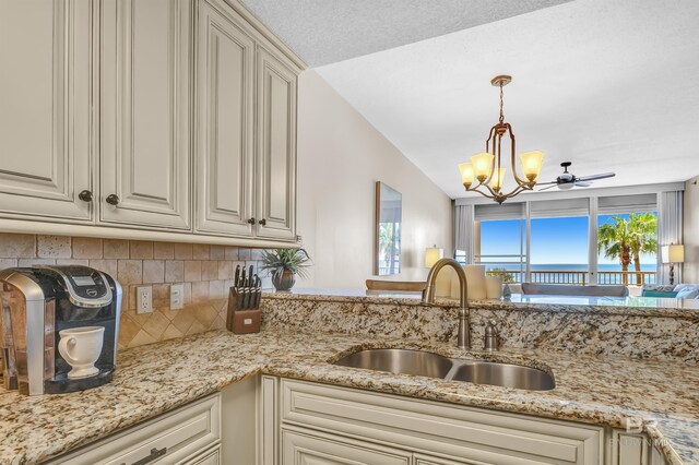 527 Beach Club Trl Unit C305, Gulf Shores, AL 36542 - kitchen featuring a sink, a water view, a notable chandelier, backsplash, and light stone counters