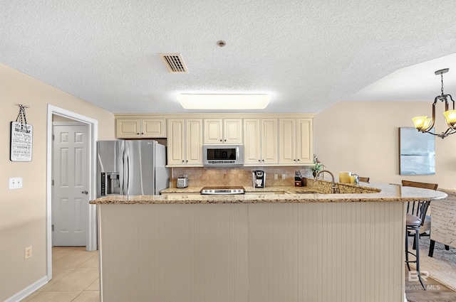 527 Beach Club Trl Unit C305, Gulf Shores, AL 36542 - kitchen with a kitchen breakfast bar, visible vents, a chandelier, appliances with stainless steel finishes, and cream cabinets