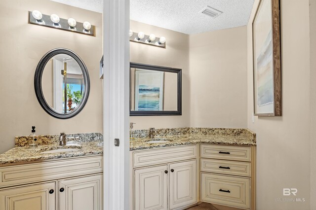 527 Beach Club Trl Unit C305, Gulf Shores, AL 36542 - full bathroom with visible vents, two vanities, a textured ceiling, and a sink