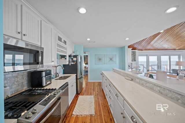316 Quivira St, Dauphin Island, AL 36528 - kitchen featuring tasteful backsplash, white cabinetry, a sink, stainless steel appliances, and light wood finished floors