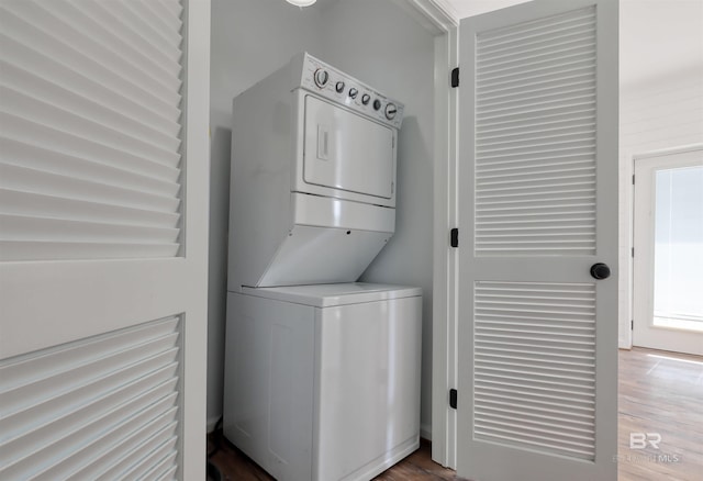 washroom featuring stacked washer / dryer, wood finished floors, and laundry area