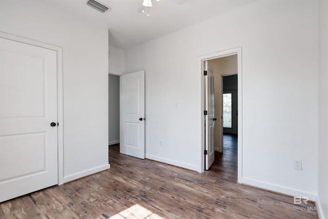 unfurnished bedroom with baseboards, wood finished floors, and visible vents