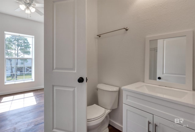 half bath featuring toilet, a ceiling fan, vanity, and wood finished floors