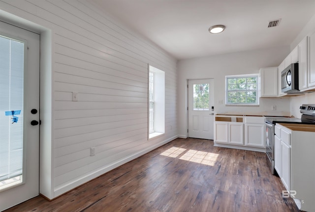 kitchen with white cabinets, stainless steel appliances, visible vents, and dark wood finished floors
