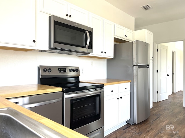 kitchen with butcher block counters, white cabinetry, appliances with stainless steel finishes, and dark wood finished floors