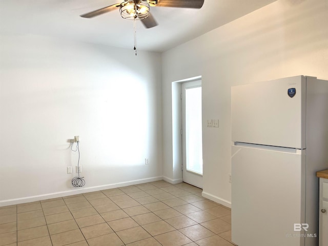 empty room featuring a ceiling fan, baseboards, and light tile patterned flooring