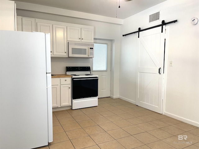 kitchen featuring a barn door, light tile patterned flooring, visible vents, white cabinetry, and white appliances