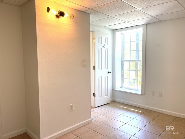 empty room with a wealth of natural light, baseboards, and light tile patterned floors
