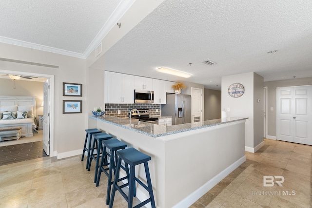 375 Beach Club Dr Unit 1801, Gulf Shores, AL 36542 - kitchen featuring appliances with stainless steel finishes, a textured ceiling, decorative backsplash, light stone counters, and baseboards