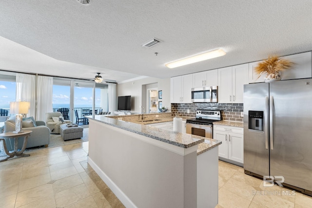 375 Beach Club Dr Unit 1801, Gulf Shores, AL 36542 - kitchen featuring stainless steel appliances, open floor plan, a peninsula, white cabinetry, and backsplash