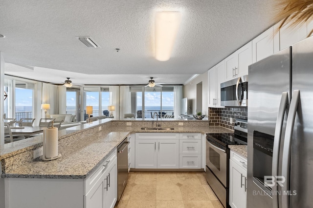375 Beach Club Dr Unit 1801, Gulf Shores, AL 36542 - kitchen with appliances with stainless steel finishes, a sink, a ceiling fan, white cabinetry, and a textured ceiling