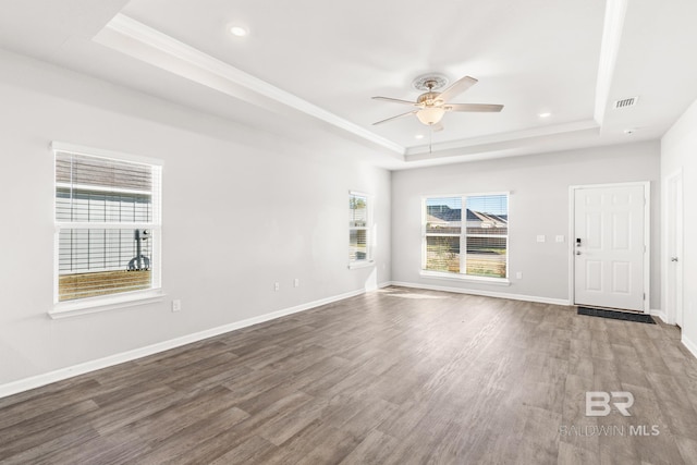 empty room with a tray ceiling, ceiling fan, and wood-type flooring