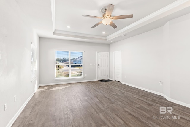 spare room with a tray ceiling, ceiling fan, and dark hardwood / wood-style flooring