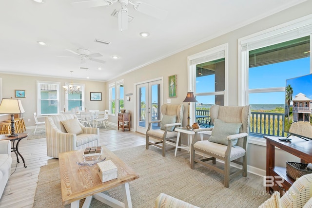 living room with ceiling fan with notable chandelier, plenty of natural light, light hardwood / wood-style floors, and crown molding