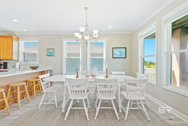 dining room featuring ornamental molding, a chandelier, sink, and light hardwood / wood-style floors