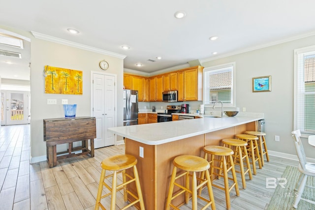 kitchen with kitchen peninsula, a kitchen bar, plenty of natural light, and stainless steel appliances