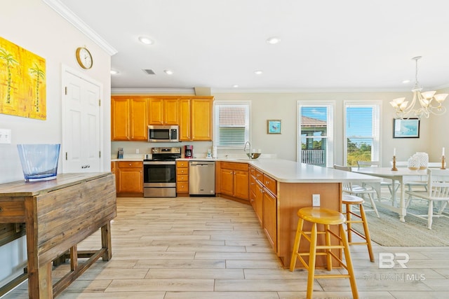 kitchen featuring stainless steel appliances, sink, pendant lighting, light hardwood / wood-style flooring, and a kitchen breakfast bar