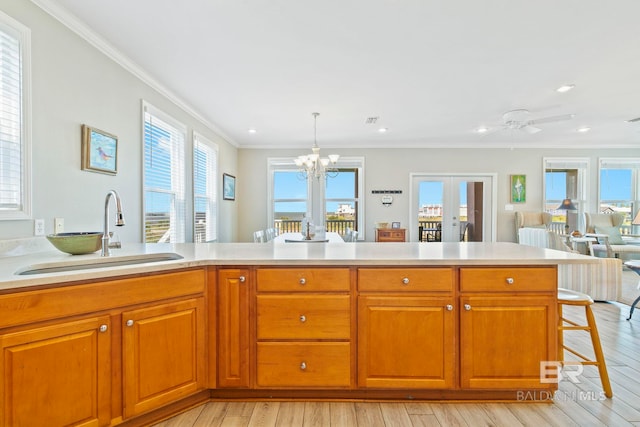 kitchen with a breakfast bar area, light hardwood / wood-style flooring, decorative light fixtures, sink, and ornamental molding