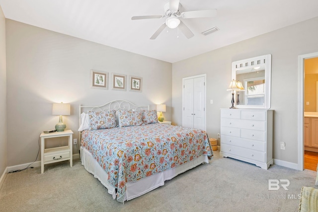 bedroom featuring light carpet, ceiling fan, ensuite bathroom, and a closet