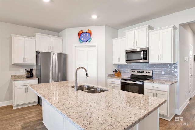 kitchen featuring appliances with stainless steel finishes, sink, wood-type flooring, white cabinets, and an island with sink