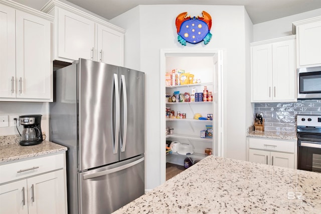 kitchen featuring decorative backsplash, appliances with stainless steel finishes, white cabinetry, and light stone counters