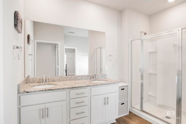 bathroom with hardwood / wood-style floors, vanity, and a shower with shower door