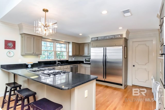 kitchen featuring kitchen peninsula, light wood-type flooring, ornamental molding, stainless steel appliances, and hanging light fixtures