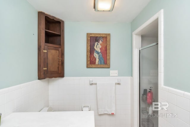 bathroom with vanity, a shower with shower door, and tile walls