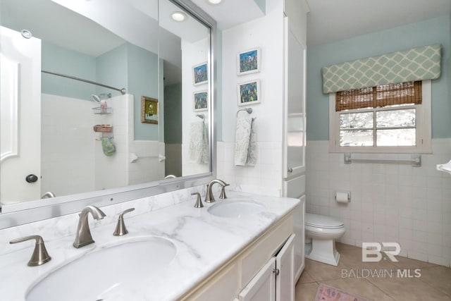 bathroom featuring tile patterned flooring, vanity, tile walls, and toilet