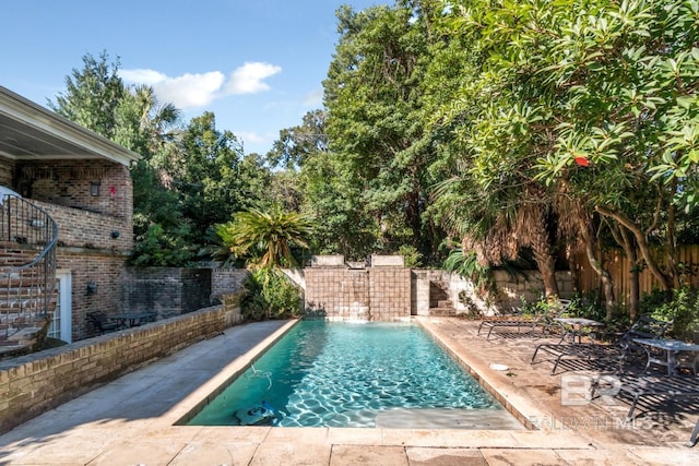 view of swimming pool with pool water feature and a patio