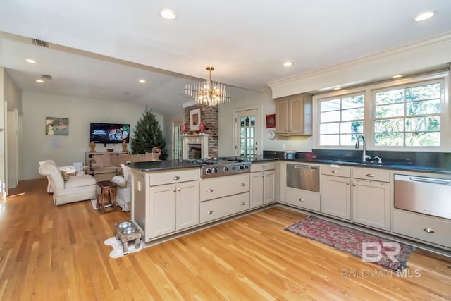 kitchen with stainless steel gas stovetop, light hardwood / wood-style floors, kitchen peninsula, and hanging light fixtures