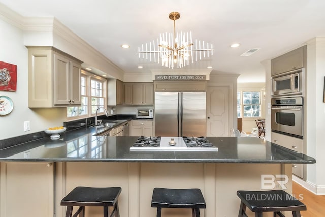 kitchen with sink, stainless steel appliances, light hardwood / wood-style flooring, a notable chandelier, and a breakfast bar area