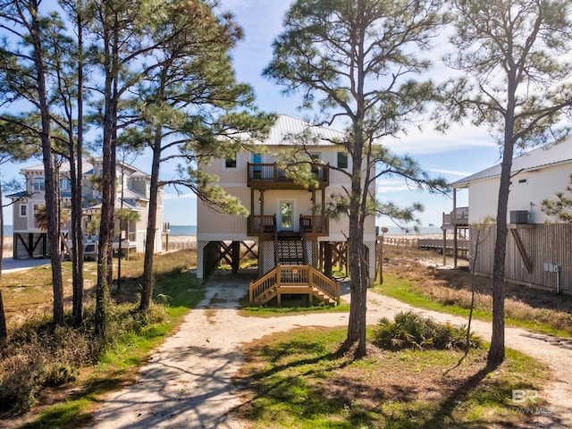 exterior space featuring stairs, a balcony, dirt driveway, and fence