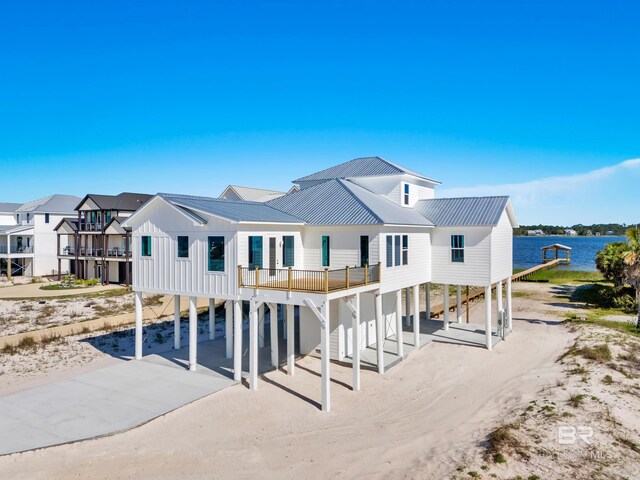 2270 W Beach Blvd, Gulf Shores, AL 36542 - back of house with a carport, concrete driveway, metal roof, a residential view, and a water view