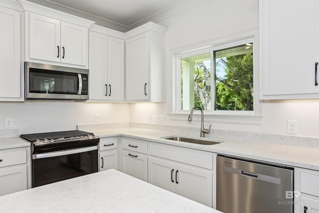 5099 Leeward Dr, Pensacola, FL 32507 - kitchen featuring stainless steel appliances, a sink, white cabinetry, and light stone countertops
