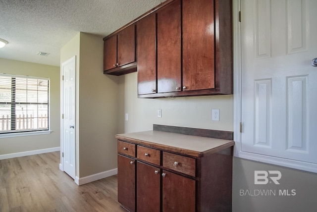 kitchen with light hardwood / wood-style floors, dark brown cabinets, and a textured ceiling