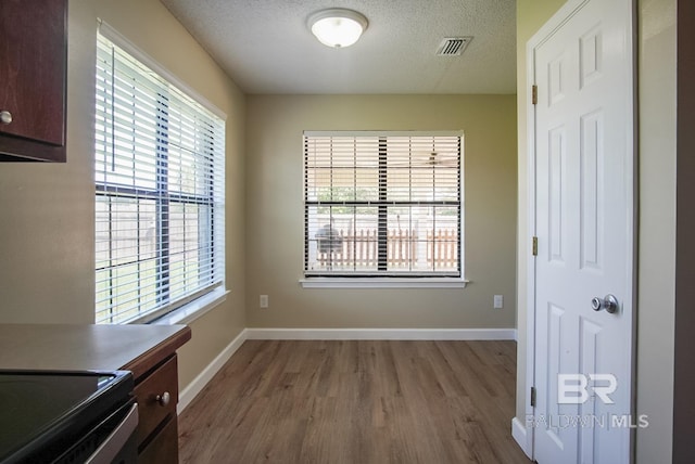 unfurnished dining area featuring light hardwood / wood-style floors and a textured ceiling