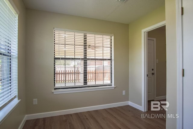 unfurnished room featuring wood-type flooring and a textured ceiling