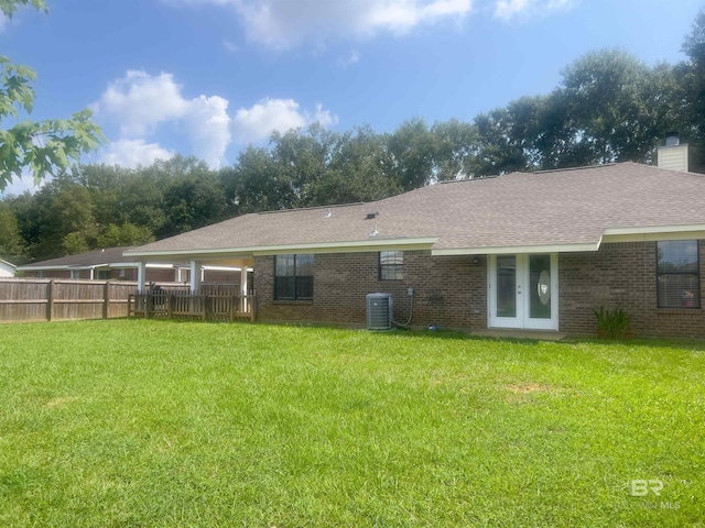 rear view of house with a yard, central AC unit, and french doors