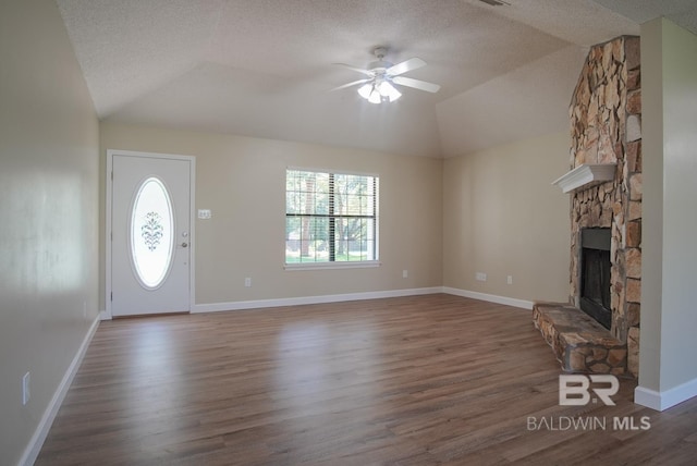 unfurnished living room featuring lofted ceiling, ceiling fan, dark hardwood / wood-style floors, a fireplace, and a textured ceiling