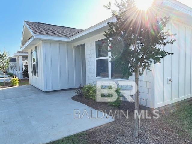 view of side of property with a shingled roof and board and batten siding