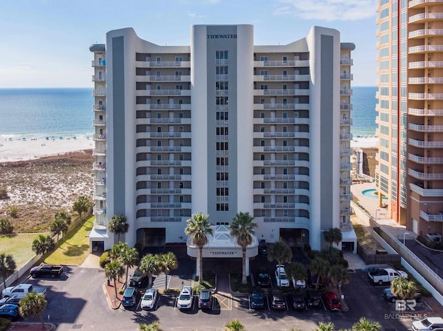 view of building exterior featuring a view of the beach, uncovered parking, and a water view