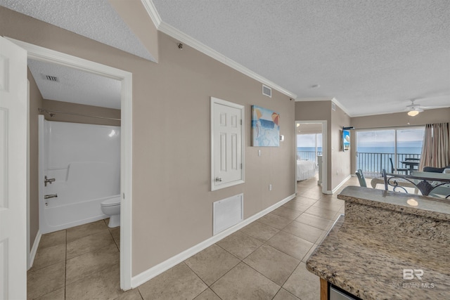 interior space with visible vents, a textured ceiling, and ornamental molding